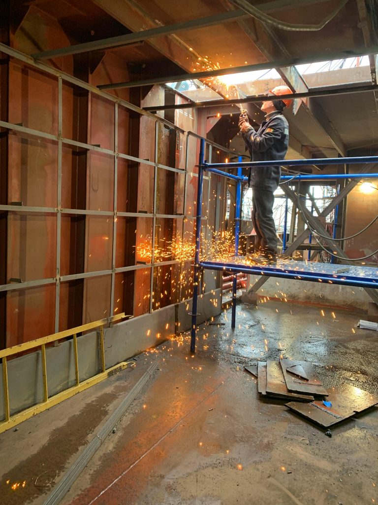 pexels-photo-4025501-4025501 A construction worker welds metal indoors, creating flying sparks in a factory setting.